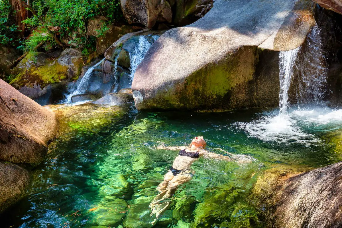 a woman lying in water with a waterfall - Hot Springs in Arizona